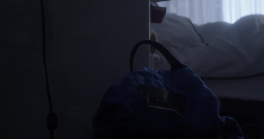 A bag sits by the bed of a sleeping person
