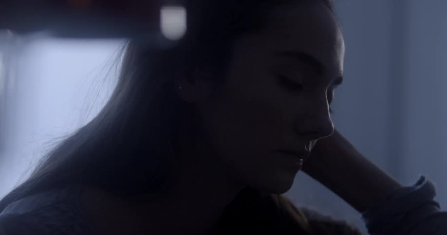 A woman is getting up in her dark bedroom