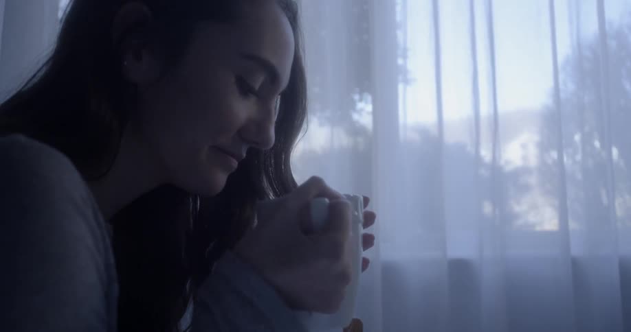 A lady is sitting in bed drinking a cup of tea