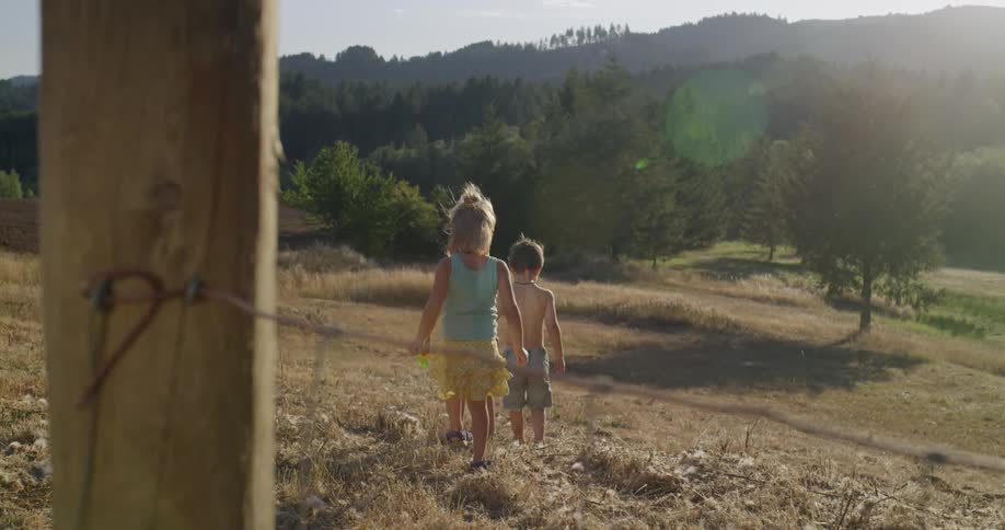 Children walk down a hill in the sunshine