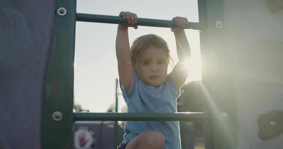 A small child is climbing up some playground equipment