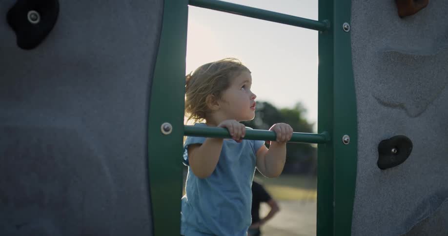 Small child climbs on playground equipment
