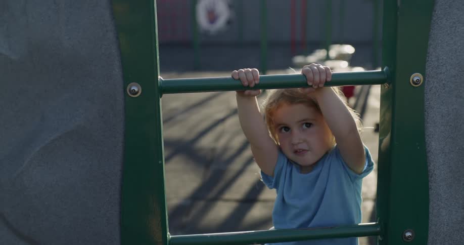A little girl is climbing on playground equipment