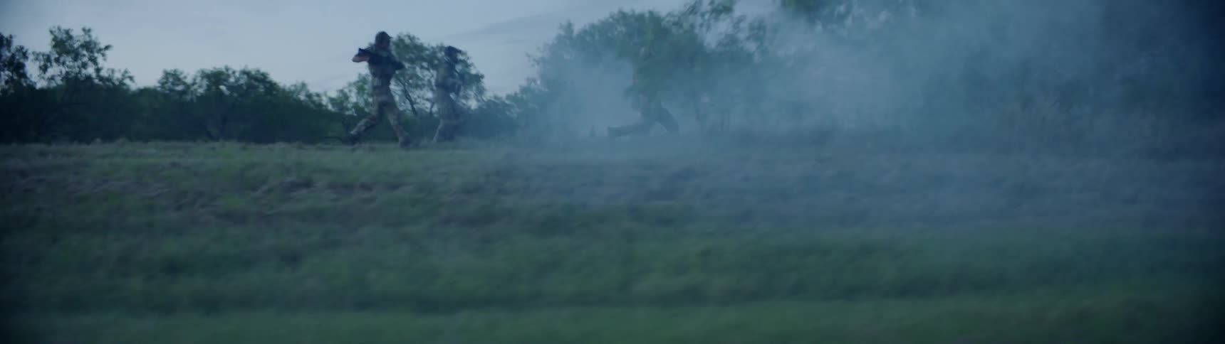 Soldiers race across the field towards smoke