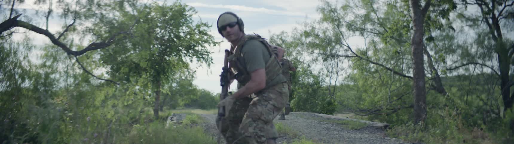 Soldiers run along the trail as one watches out