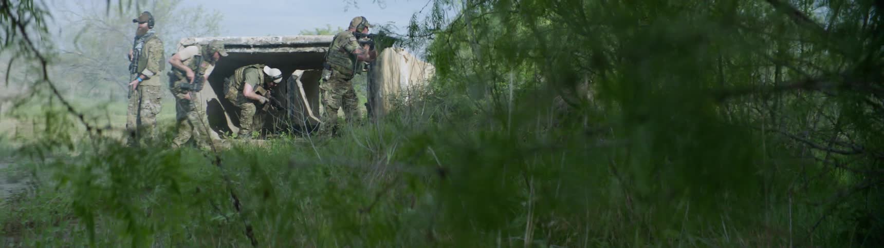 Men with machine guns crouch down as one scans the area