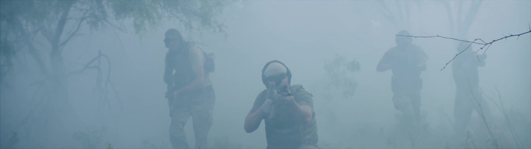 Army of men walking through fog and trees and aiming rifles
