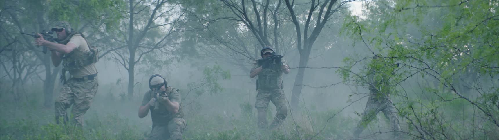 An army unit is walking through a misty forest with guns