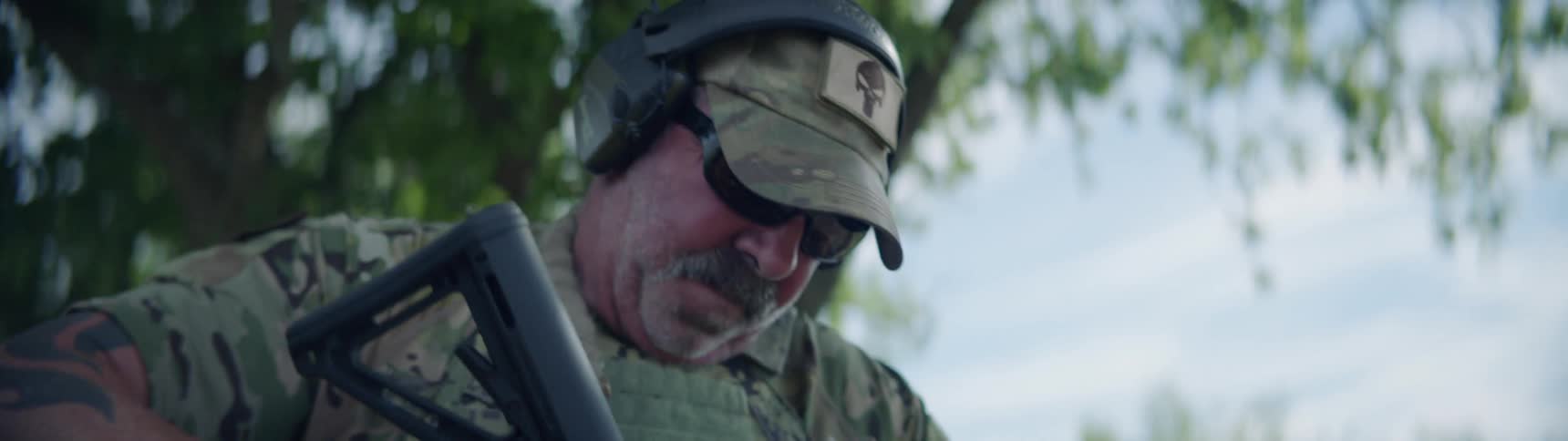 A man in a military uniform is loading his rifle during the day