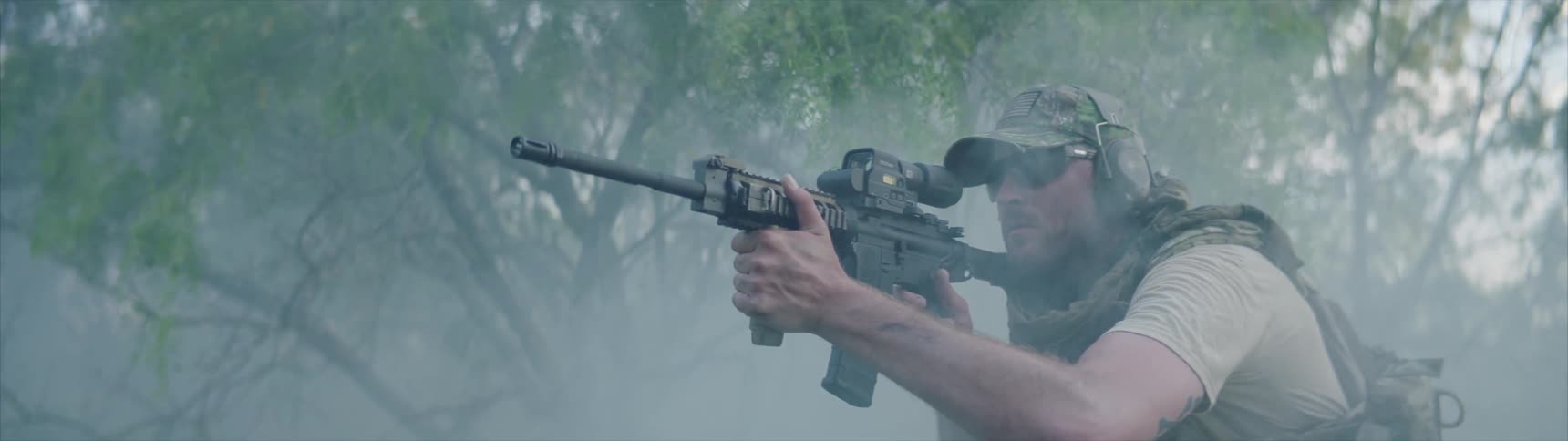 A soldier fires his rifle in the smoke