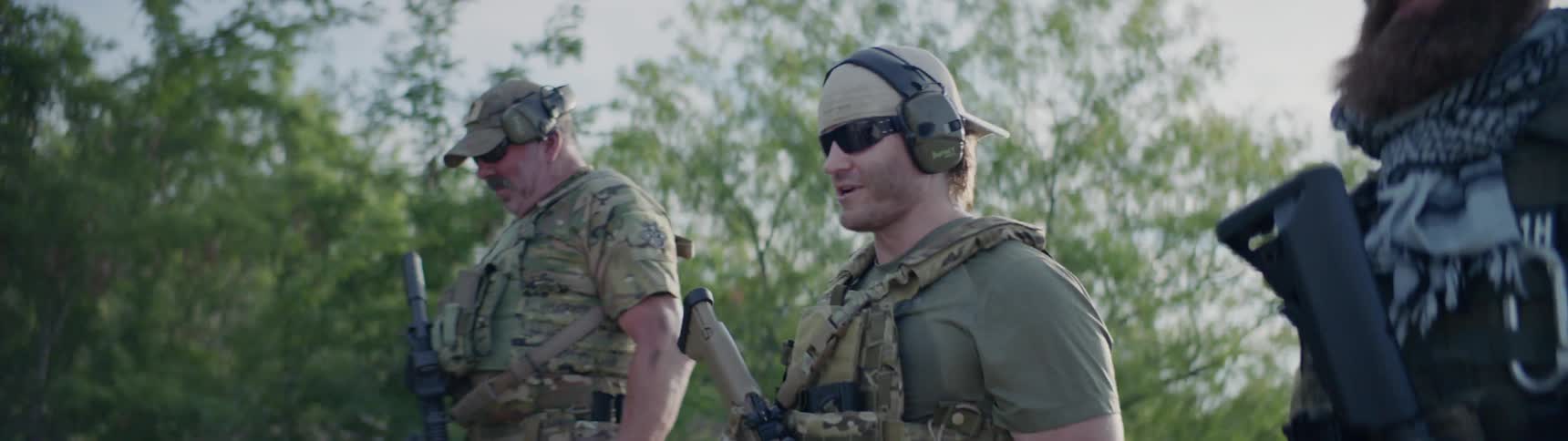 Gun carrying soldiers walk near trees