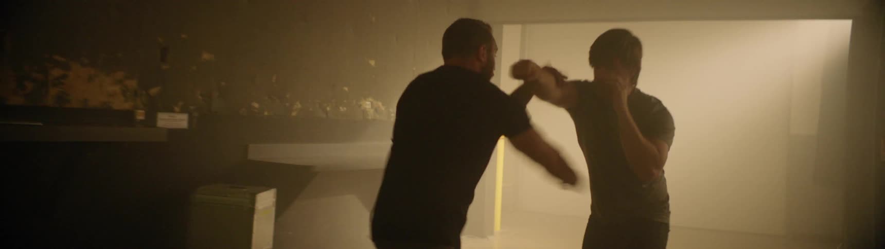 Two people spar in the dark room