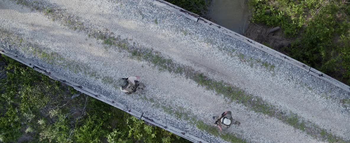 Soldiers run across a rural bridge with guns