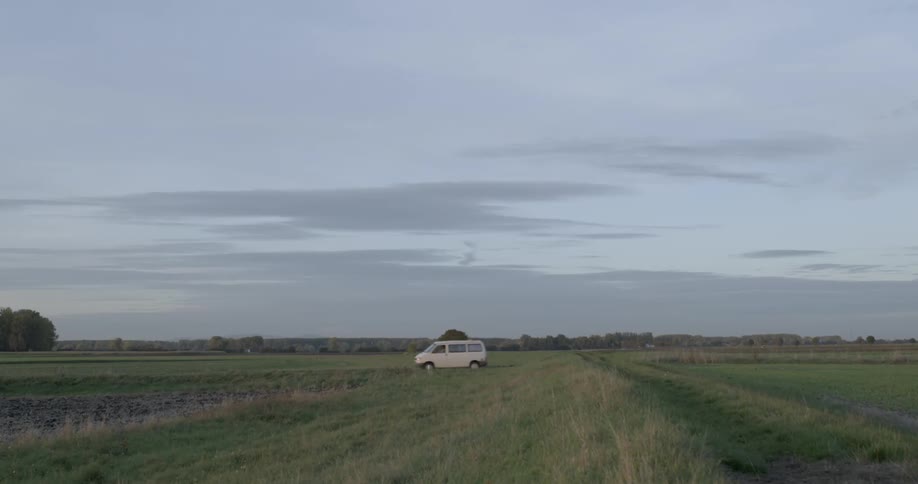A van drives on a road in a grassy field