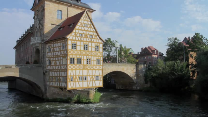 A river is flowing beneath a medieval building on a bridge during the day