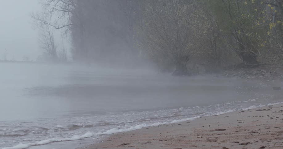 Ocean waves wash ashore on a foggy day