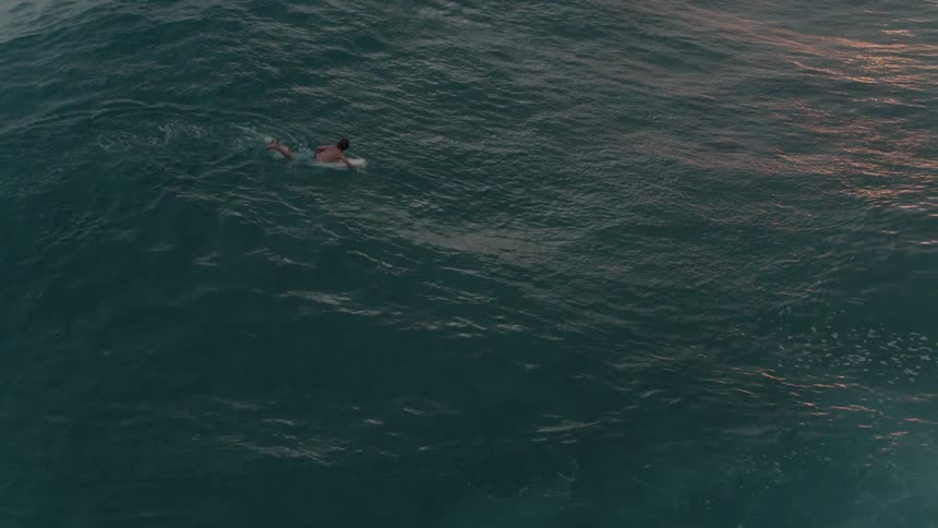Man paddles a surfboard out to sea