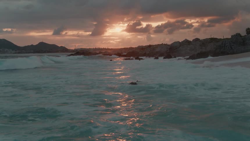 Ocean waves wash ashore at sunset