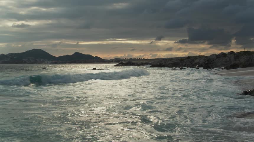 Waves coming ashore on a beach on a cloudy day