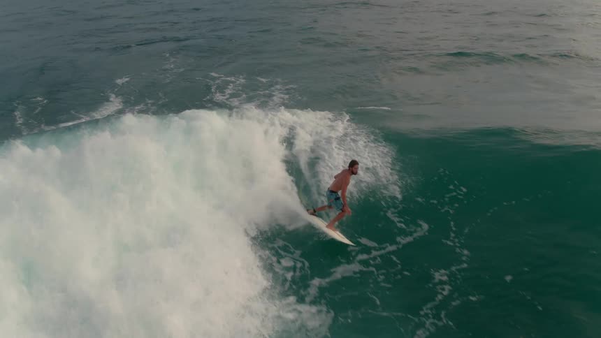 A surfer paddles and rides the wave