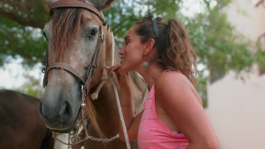 Woman smiles while petting and kissing a horse