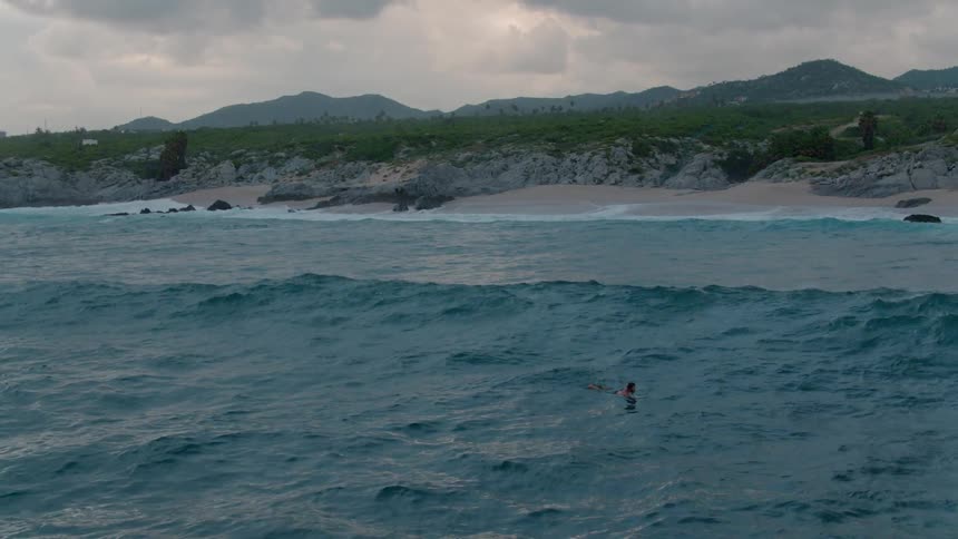A surfer paddles in the water