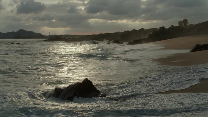 Waves coming ashore on a beach on a cloudy day