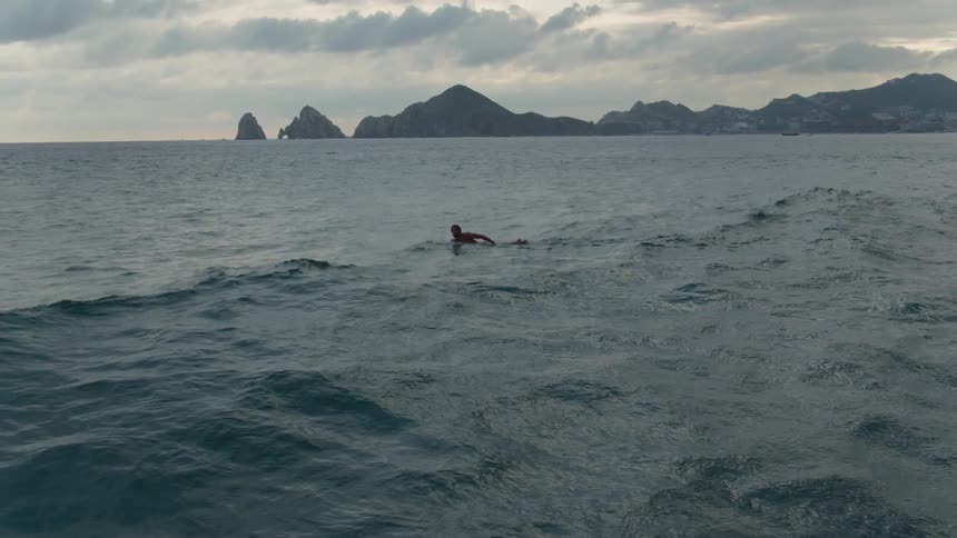 A person is swimming on his board in the water