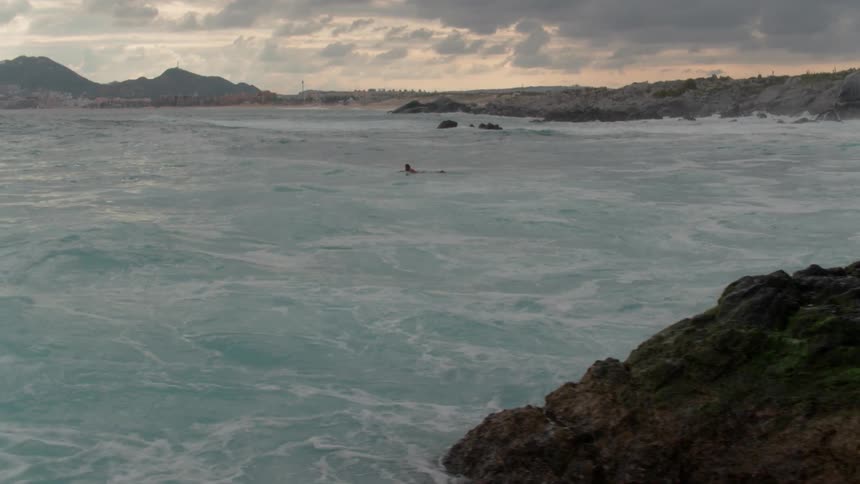 Lone person in a large body of water on a cloudy day