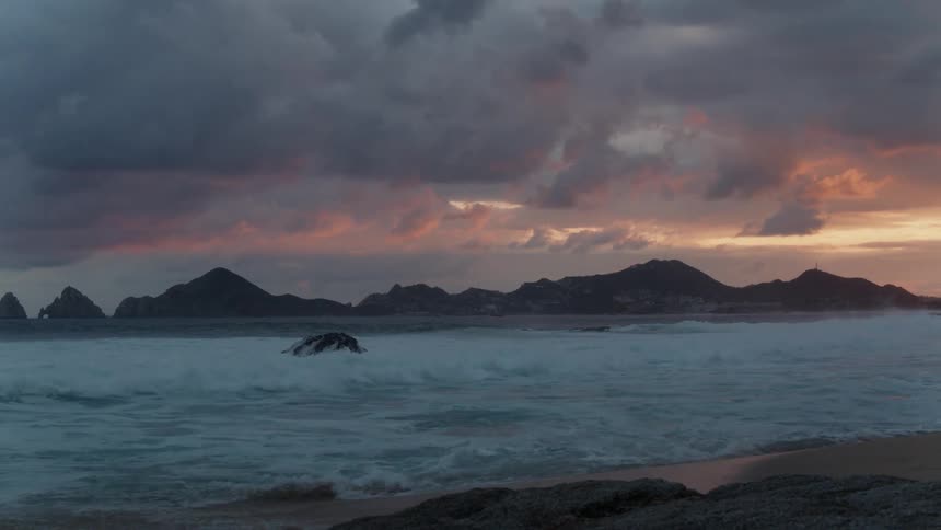Waves coming ashore on a beach on a cloudy day at sunset