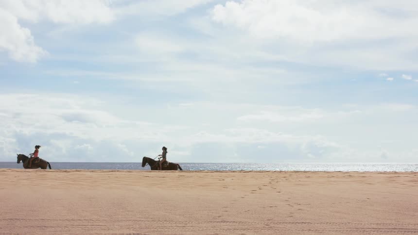Women ride along the beach