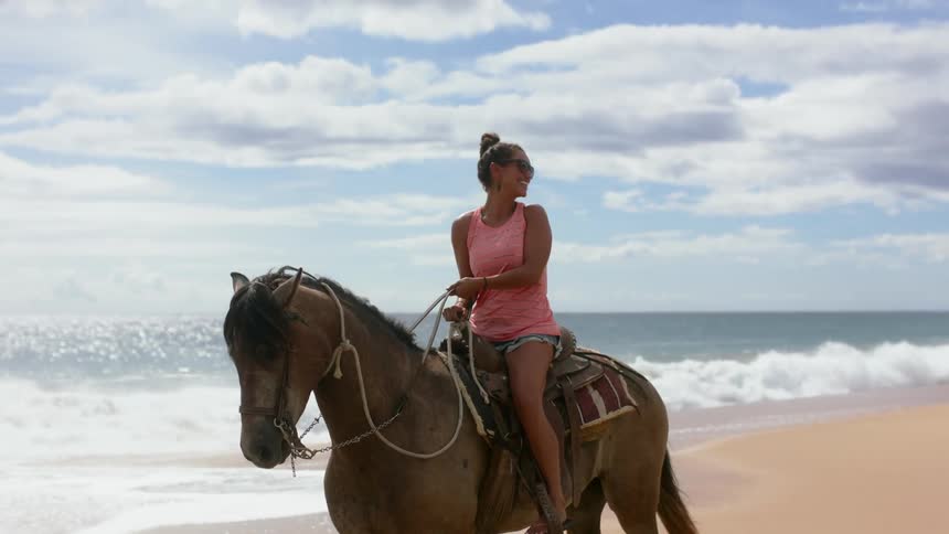 Woman rides a horse on the beach