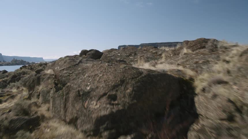 Ascending low over a rocky hillside to reveal a calm and beautiful plateau lake