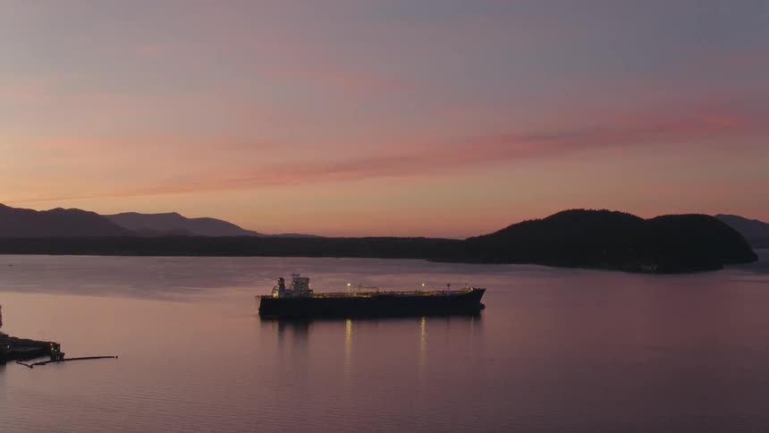 Oil tanker anchored near a petroleum terminal under a stunning sunset
