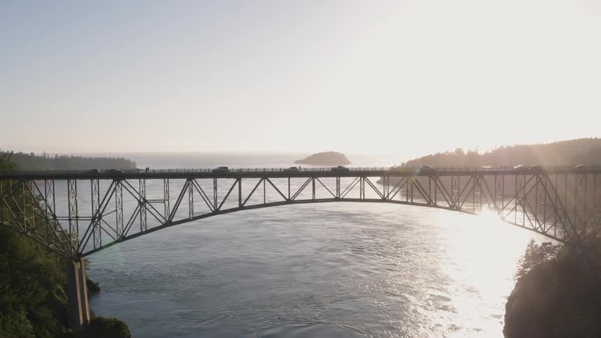 Reveal of cars driving on a beautiful backlit bridge connecting two islands