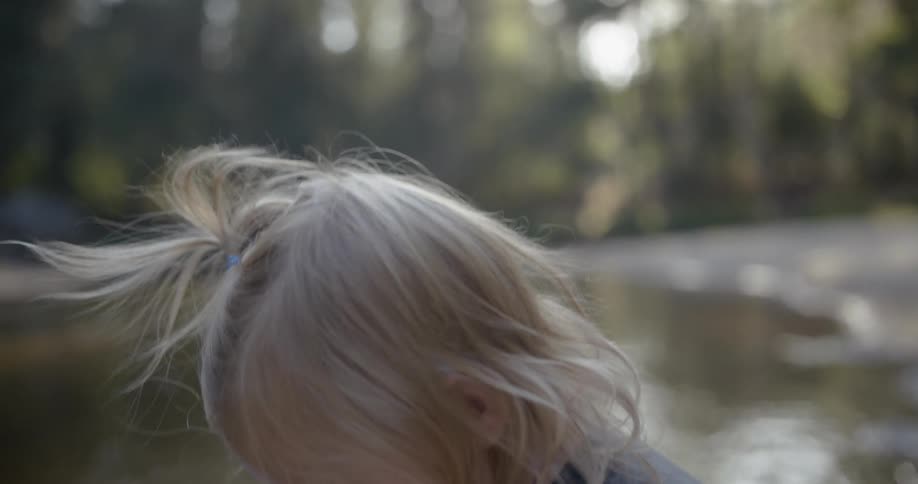 A young girl leans down towards the stream