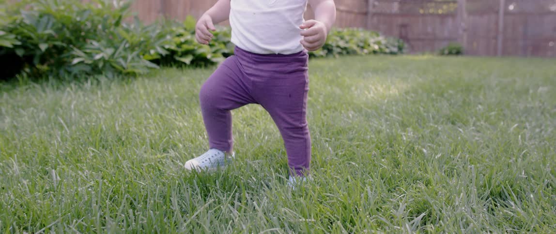 A young girl waddles in the yard