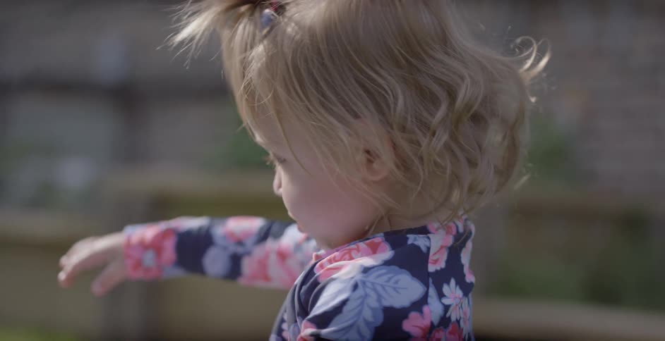 A toddler plays in a backyard