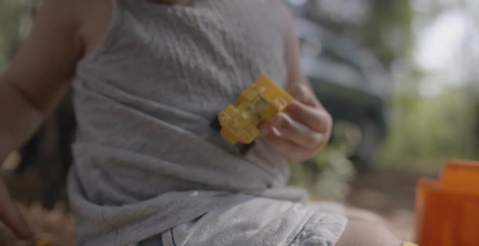 A child is playing with toy trucks in the grass