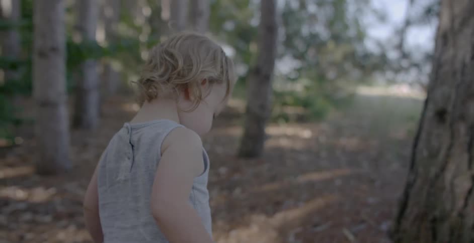 A young child plays out in nature