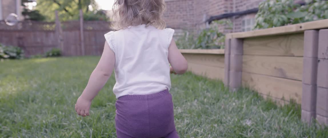 A toddler crosses the yard