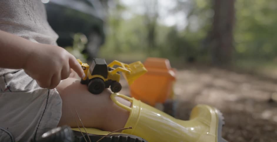 A young girl plays with toys in the dirt