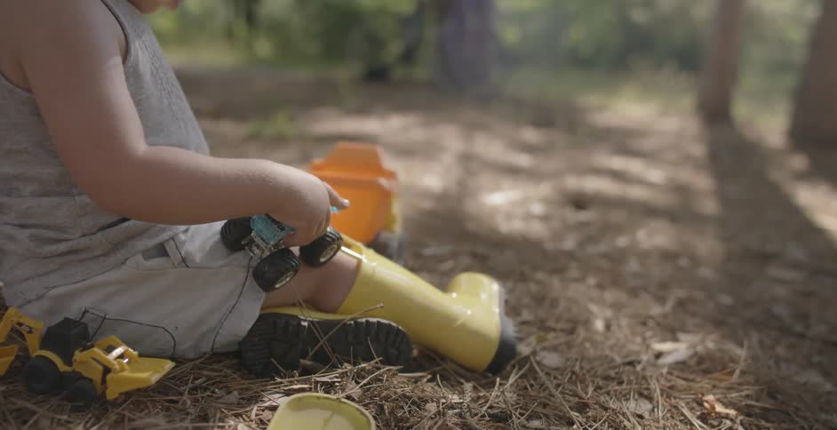 A young girl plays with toys in the dirt