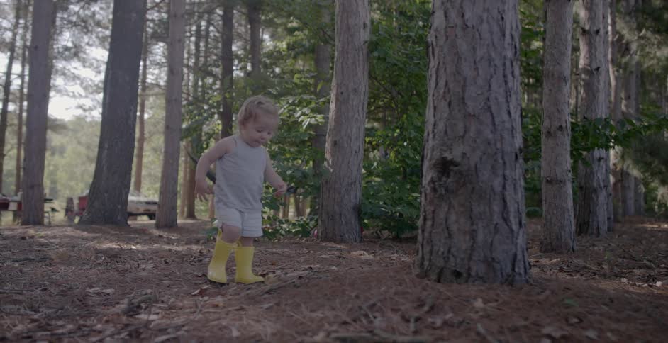 A young girl walks by tall trees in the forest