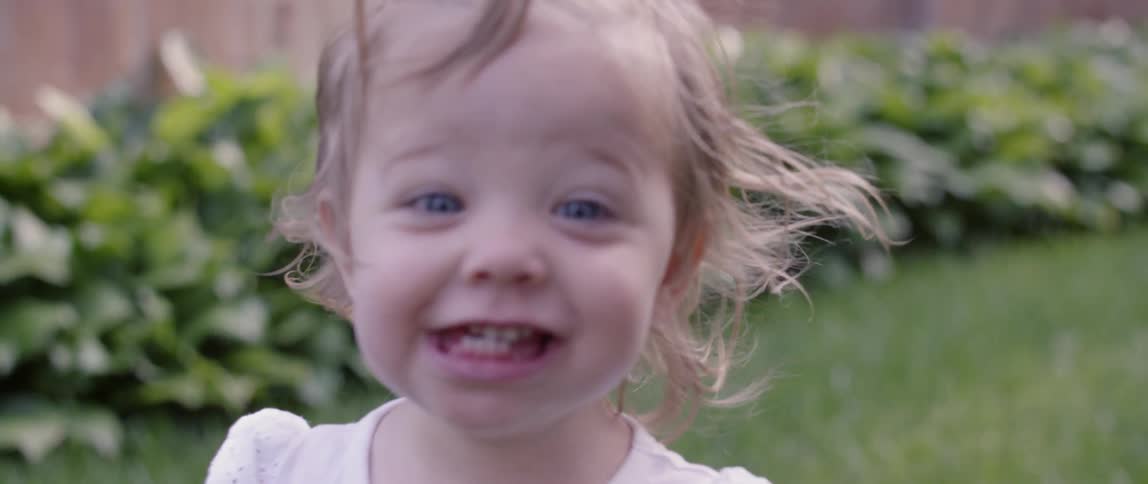 A baby laughing at bubbles outside