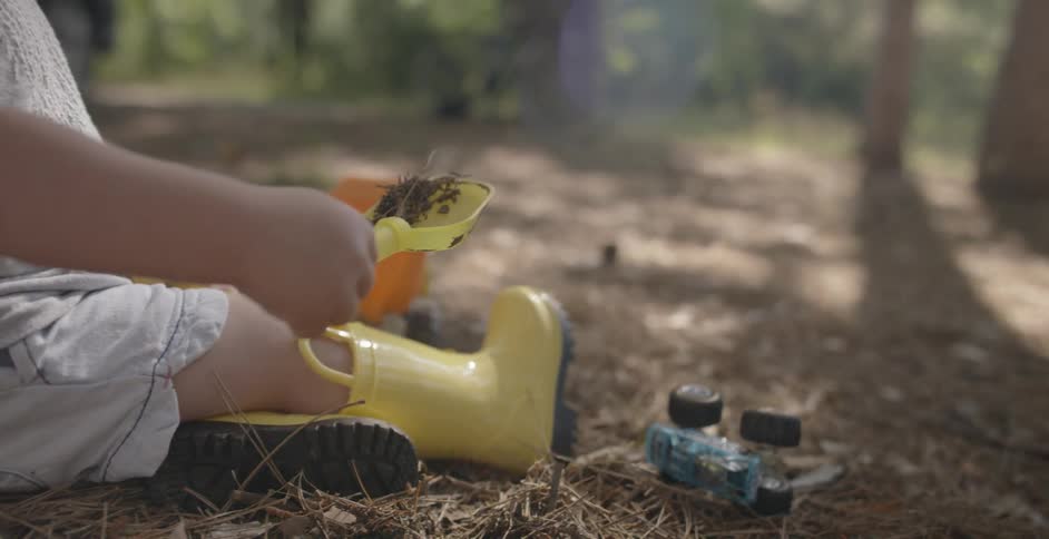 A child is digging in the dirt with a toy shovel