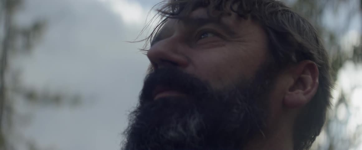 A bearded man walks out in nature
