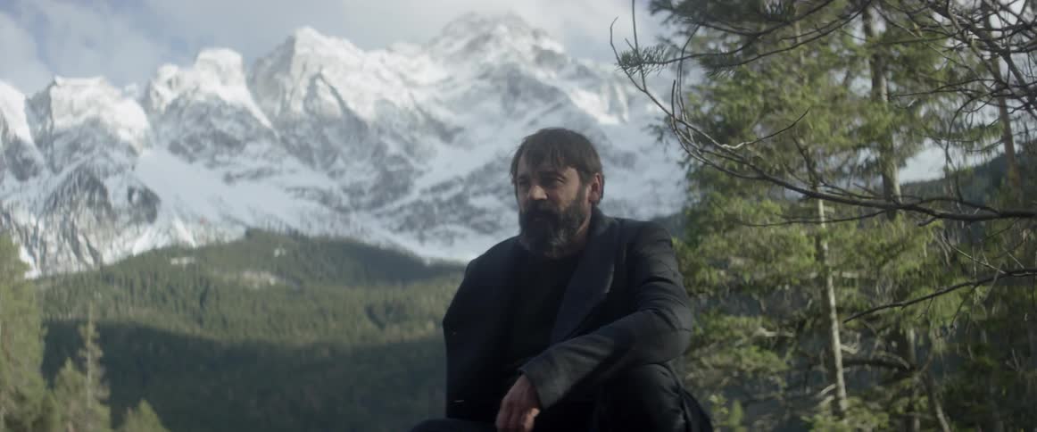 A man is sitting in thought in a mountain setting in winter
