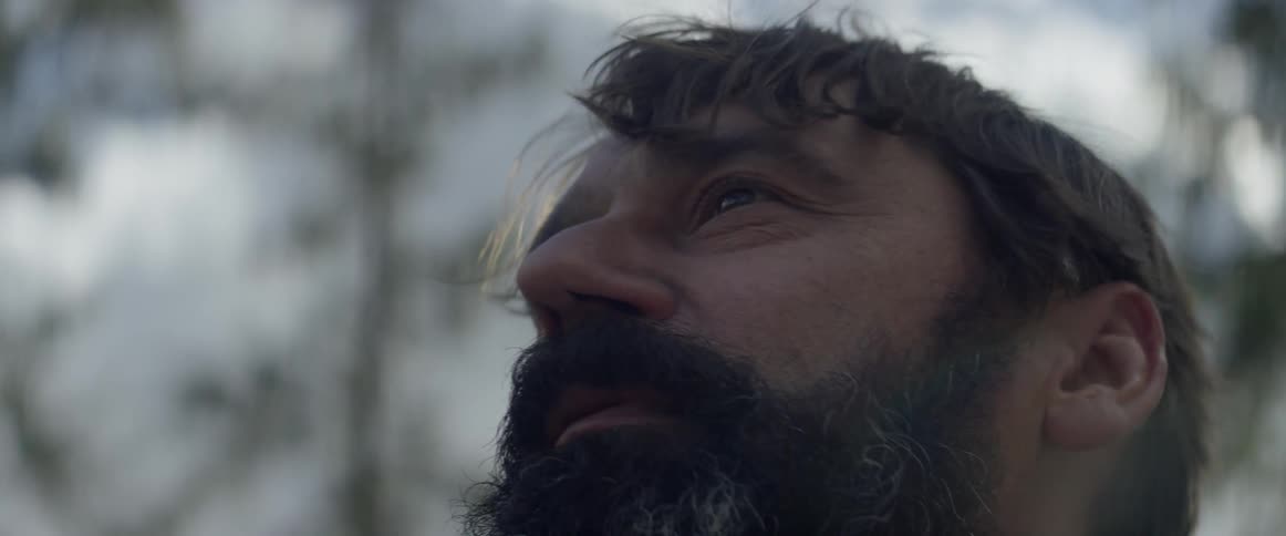 A man stops walking to look around at his environment in a natural setting