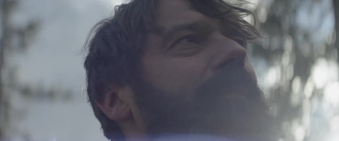 A bearded man looks around outside